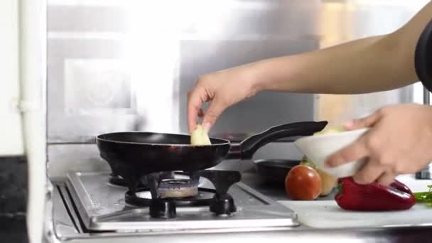 一个拉丁女人的手的特写镜头 她把菜刀扔到油锅里煎 — 图库视频影像