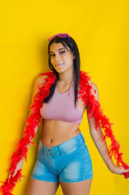 Karnaval kıyafetleri içinde esmer Latin bir kadın. Sarı arka planda çok mutlu poz veriyor.