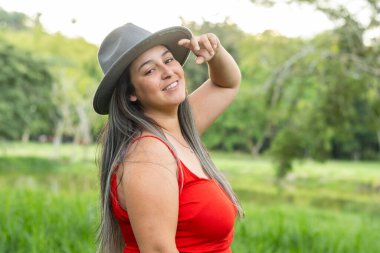 Çok mutlu bir Latin kadın kırsalda yürürken gülümsüyor ve bir tarafa bakıyordu.