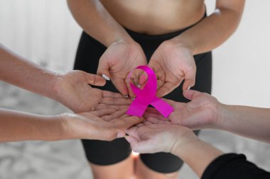 Bir grup kadın, göğüs kanserine karşı verilen mücadelenin sembolü olan pembe kurdeleyi tutmak için el ele tutuşuyor..