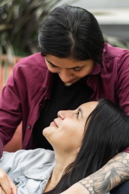 Latin kadın kafasını bacaklarının arasına almış kız arkadaşına bakıyor. Lezbiyen çift birbirini çok seviyor.