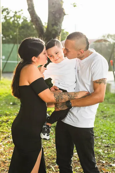 Latin bir çift oğlunu öpmeye çalışırken kucağına alıyor ve çocuk onu öpmelerine izin vermiyor.