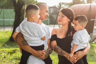 Genç Kolombiyalı çift, birbirlerinin yüzlerine bakarken küçük çocuklarını kollarında tutuyor..