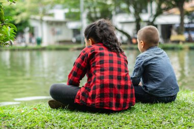 İki çocuk sırtüstü parktaki göle bakıyor.