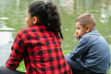 Çocuklar parkta sohbet ederken göle bakıyorlar.