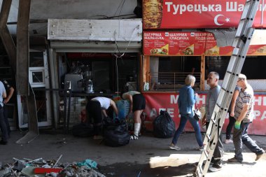 DNIPRO, UKRAINE - 08.24.20: bir Rus roketi Dnipro otobüs durağına çarptı. Otobüs durağı, dükkanlar ve ticaret kulübeleri yıkıldı. İşçiler hasarı temizler