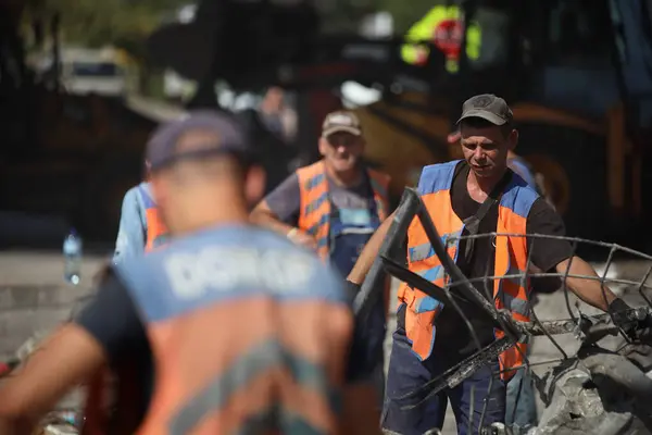 DNIPRO, UKRAINE - 08.24.20: bir Rus roketi Dnipro otobüs durağına çarptı. Otobüs durağı, dükkanlar ve ticaret kulübeleri yıkıldı. İşçiler hasarı temizler