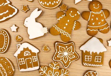 Tahta bir masada farklı şekillerde zencefilli kurabiyeler, yakın plan. Tavşan şeklinde zencefilli kurabiye, zencefilli kek kadın, kar tanesi evi ve zencefilli ekmek adam.