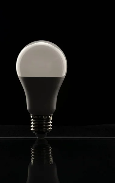 White LED lamp on a black background. The concept of saving electricity