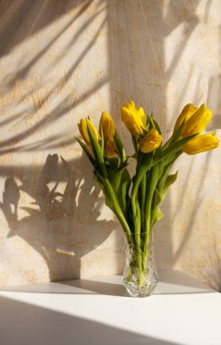 Yellow tulips in a vase in the evening rays of the sun. Holiday celebration concept. Interior decoration
