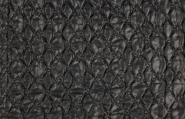 A pattern on a black leather surface. Black leather texture background close-up