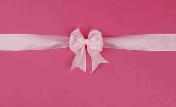 Pink bow with ribbon isolated on pink background. View from above. Gift decoration concept