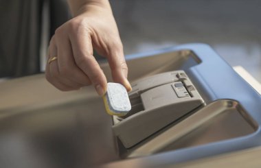 Bir el bulaşık makinesinin içine bir kapsül koyar. Bulaşık konsepti