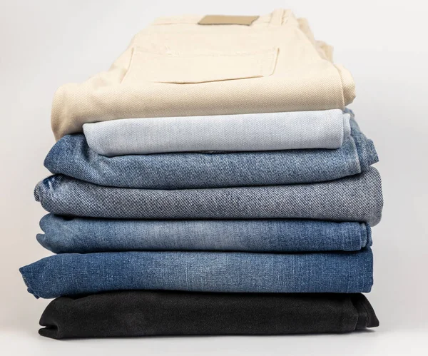 A pile of different jeans, on a white background. The concept of updating the wardrobe