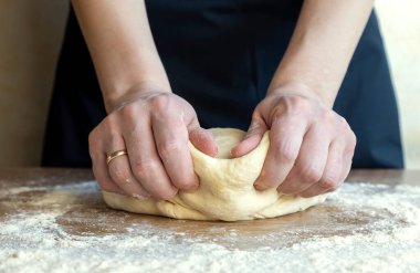 Hamur yapmak, ekmek pişirmek için hamur yoğuran kadın elleri.