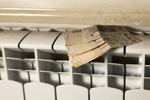 Money bills on a heating radiator. Payment of bills, heating season. The concept of warmth and comfort at home