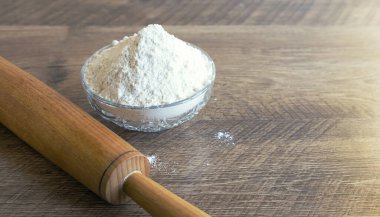 Tahta ahşap merdane ve un kaplı kase, ön manzara. Pişirme kavramı