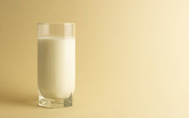 Bej arka planda bir bardak süt izole edilir. Süt ürünlerini kapatın.