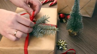 Kadınların elleri hediye kutusuna kırmızı bir fiyonk bağlar, Noel kavramı.