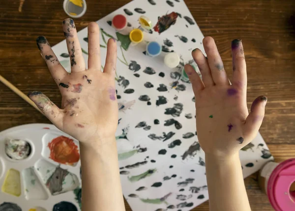 The hands of a child covered with watercolor paints. Dirty childrens hands. The concept of childrens art, child development and motor skills