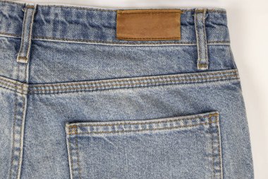 Arka planda beyaz bir kotun yakın çekimi. Mavi kot kumaşı. Denim giyim kavramı