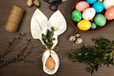 Paskalya süslemeleri yapma süreci. Tahta bir masanın üzerinde paskalya yumurtaları ve söğüt dalları