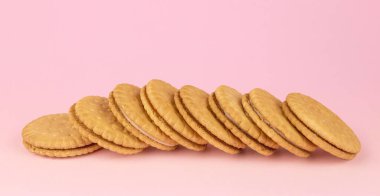 Pembe arka planda vanilyalı sandviç kurabiyeleri.