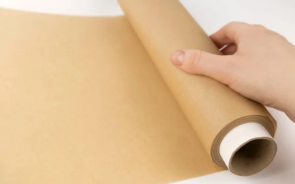 Unrolling a roll of parchment paper. A womans hand is unrolling baking paper. The concept of baking