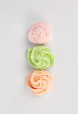 Beyaz arka planda üç tane pembe yeşil turuncu krema. Yukarıdan görüntüle.