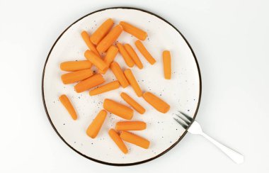 Beyaz bir tabakta bir sürü küçük havuç, üst manzara. Sağlıklı ve vejetaryen gıda kavramı