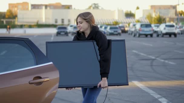 Kobieta Śmieszne Próbuje Umieścić Zakupiony Nowoczesny Telewizor Bagażniku Samochodu Sklepie — Wideo stockowe