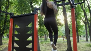 Sportif bir kadın gün batımında parkta yatay bir çubuğa yanaşıyor. Spor ve sağlıklı yaşam tarzı kavramı.
