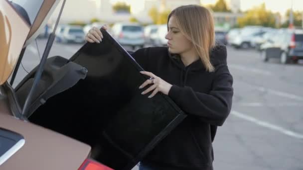 Женщина Смешно Пытается Поставить Приобретенный Современный Телевизор Багажник Автомобиля Парковке — стоковое видео