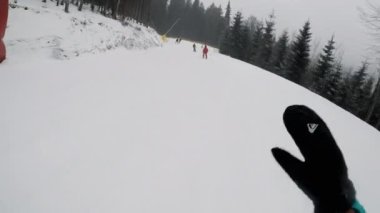 POV Snowboardcusu bir kayak merkezinde yokuş aşağı gidiyor, kış dağlarında aktif dinlenme, aksiyon kamerası