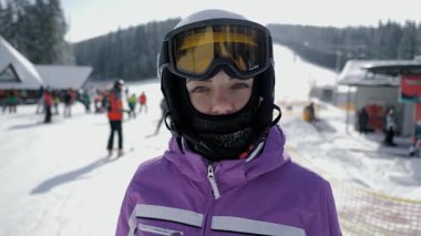 Kar kask ve gözlüklü genç bir kadının portresi karlı bir dağ yamacında duruyordu. Kış sporu yaşam tarzı, kayak merkezinde aktif tatil.
