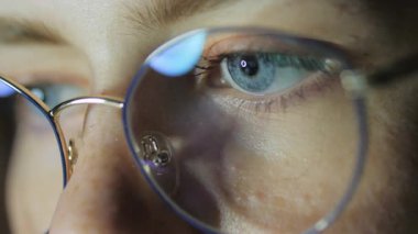 Bilgisayar ekranındaki ışığı yansıtan gözlüklü makro görüntüler. Görüş, teknoloji, dijital yaşam tarzı ve göz sağlığı kavramı. Yüksek kalite 4k görüntü