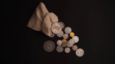      Siyah arka planda eski gümüş ve altın paraların döküldüğü bir çanta.                          