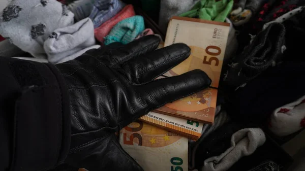 stock image a hand in a black glove takes money from a locker. thief in the apartment