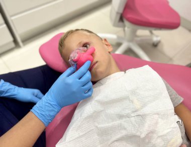 Sedation with nitrous oxide to a child. in a dental clinic clipart