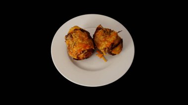              Pastırmaya sarılmış patates, üstüne peynir serpiştirilmiş ve fırında pişirilmiş. Siyah arka planda beyaz bir plaka üzerinde.                  