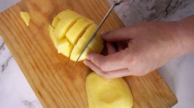      Mutfak tahtasına büyük bir bıçakla patates kes.                            