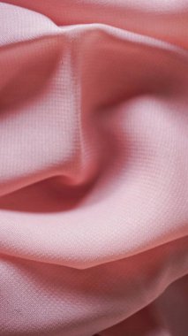 Pink silk background. The texture of the pink polycotton fabric is smooth and soft with beautiful close-up fabric details. Textile pattern with dense, breathable and flexible fibers.