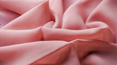 Pink silk background. The texture of the pink polycotton fabric is smooth and soft with beautiful close-up fabric details. Textile pattern with dense, breathable and flexible fibers.