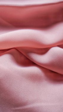 Pink silk background. The texture of the pink polycotton fabric is smooth and soft with beautiful close-up fabric details. Textile pattern with dense, breathable and flexible fibers.