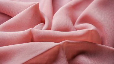 Pink silk background. The texture of the pink polycotton fabric is smooth and soft with beautiful close-up fabric details. Textile pattern with dense, breathable and flexible fibers.