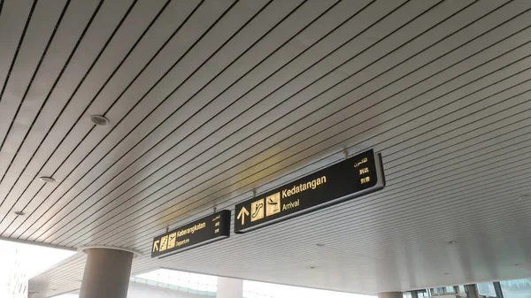 Arrival sign at the airport in Indonesian, English, Arabic and Chinese. View of the airport.