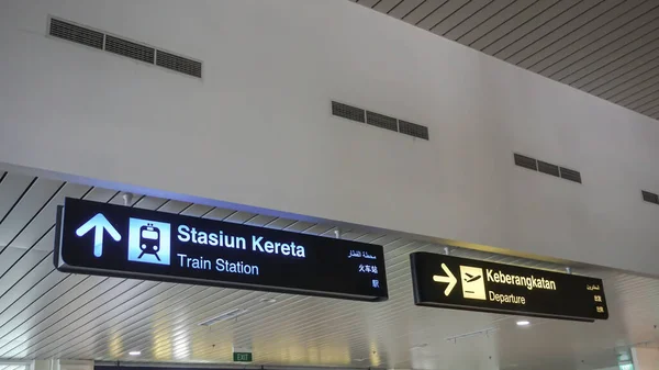 Arrival sign at the airport in Indonesian, English, Arabic and Chinese. View of the airport.