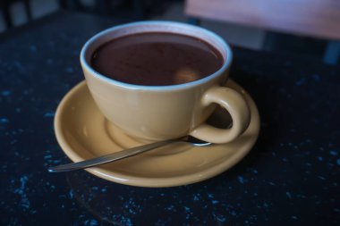 Coffee in a yellow cup on a cafe table.