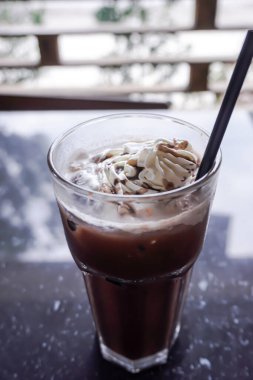 Chocolate milkshake with whipped cream and chocolate chips in glass.