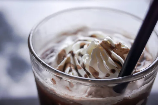 Chocolate milkshake with whipped cream and chocolate chips in glass.